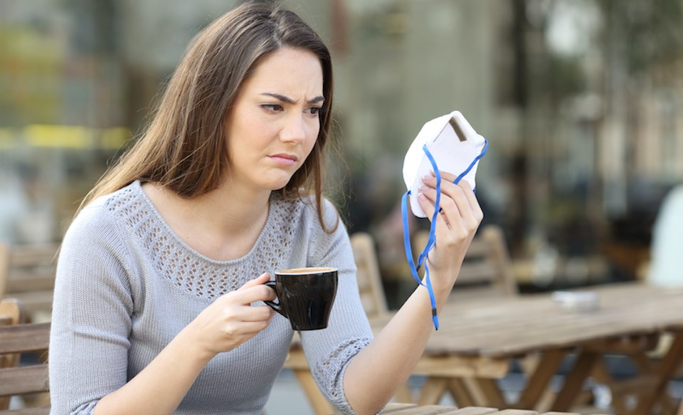 doubtful-woman-drinking-coffee-glancing-at-face-mask.jpg]